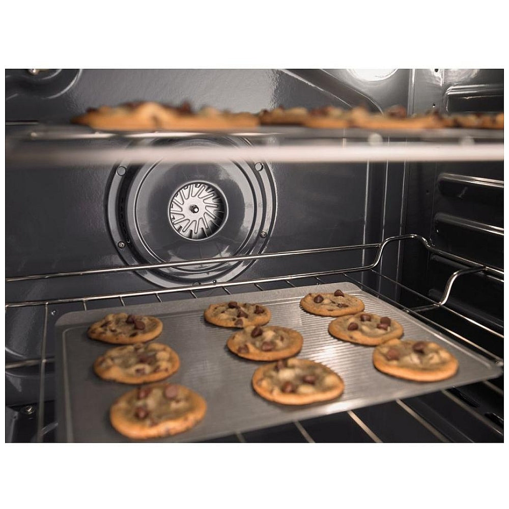 Whirlpool 30-inch slide-in electric range with cookies baking in the oven, showcasing the even heat distribution of the convection cooking system.
